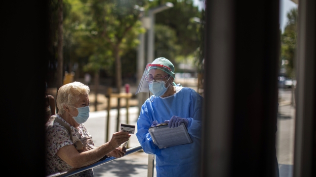 Medical worker greets a patient at hospital near Barcelona, Spain, where COVID-19 infections are spiking anew.
