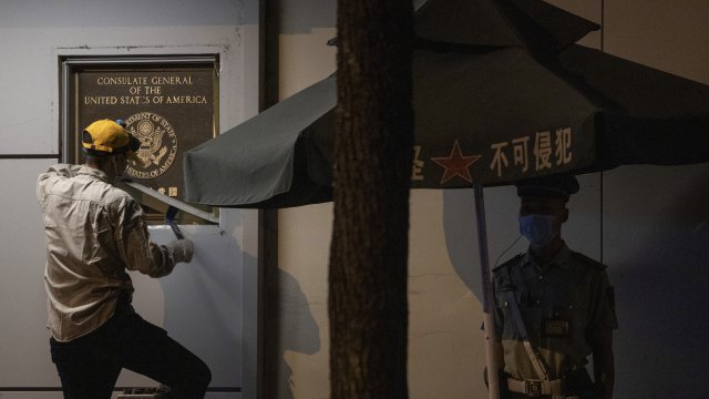 A worker tries to remove the plaque from the United States Consulate  in Chengdu.