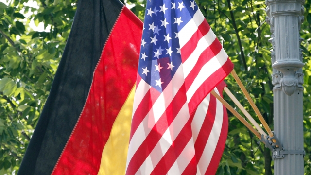 The German and U.S. flags fly on a lamp post in front of the White House.
