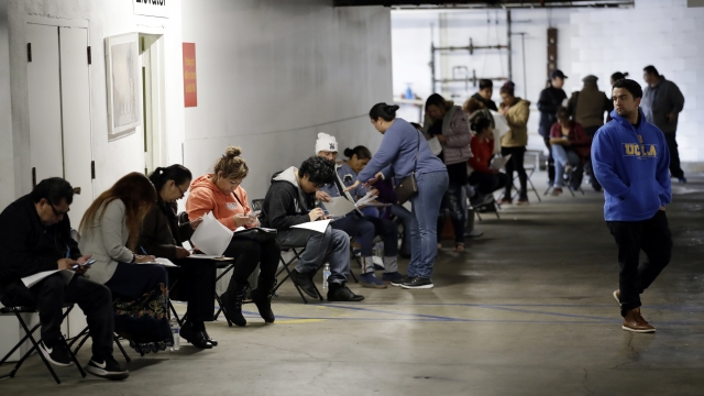 Unionized hospitality workers wait in line in a basement garage to apply for unemployment benefits