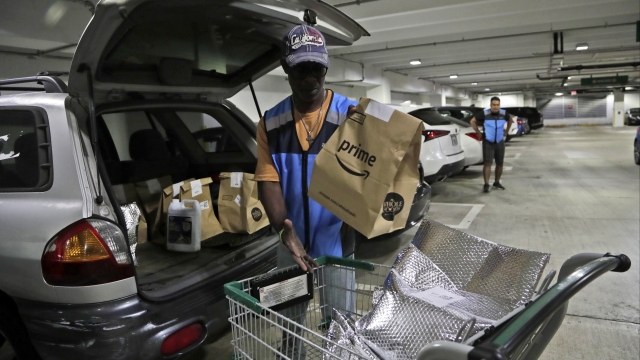 Delivery worker for Amazon Prime loads car with groceries