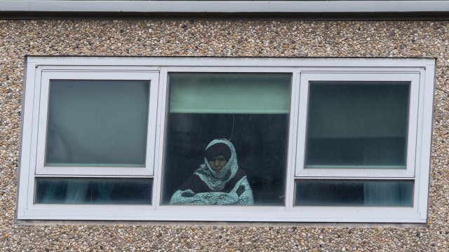 A woman looks out a window from a locked-down public housing tower in Melbourne.