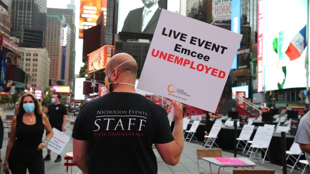 Man walks across Times Square with sign that says "LIVE EVENT Emcee UNEMPLOYED."