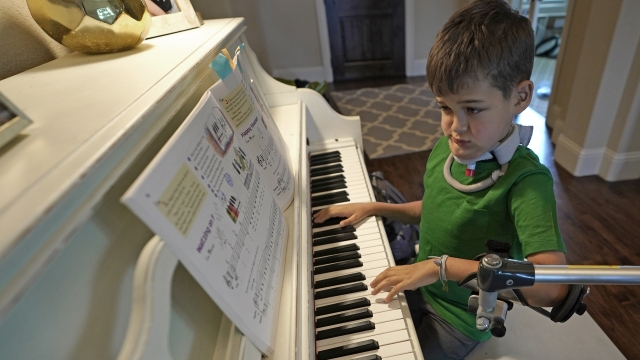 A child diagnosed with acute flaccid myelitis practices playing the piano.