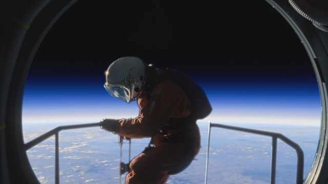 An astronaut climbs out of ship overlooking a planet.