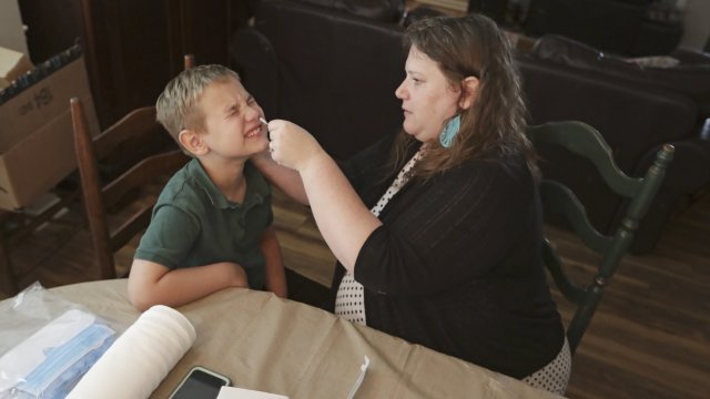 Mendy McNulty swabs the nose of her son, Andrew, 7, Tuesday, July 28, 2020, in their home in Mount Juliet, Tenn.