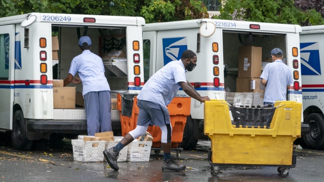 Letter carriers load mail trucks for deliveries at a U.S. Postal Service facility in McLean, Va.