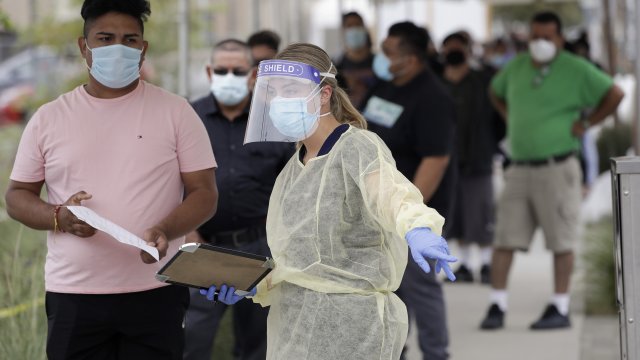 People line up behind a health care worker at a mobile Coronavirus testing site in Los Angeles, California.