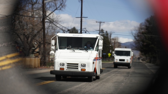 Mail carrier trucks driving down the street