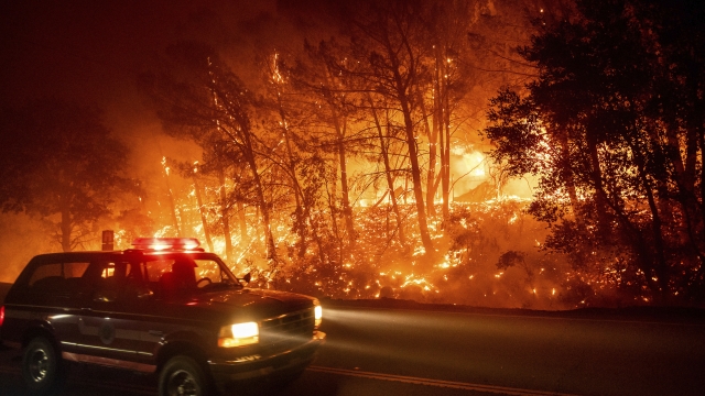 Fire crew vehicles passes burning trees in Winters, California on Wednesday.