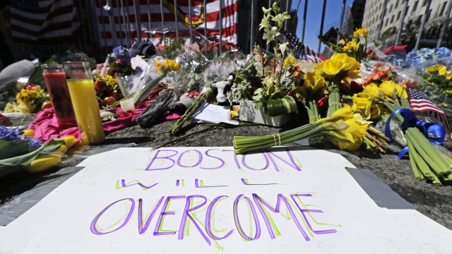 Flowers and signs adorn a barrier, two days after two explosions killed three and injured hundreds in Boston