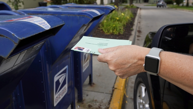 A person drops applications for mail-in-ballots into a mail box in Omaha, Nebraska