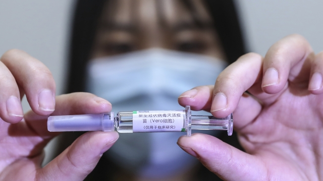 Chinese staff member holds up potential COVID-19 vaccine