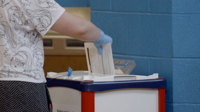 A Washington, D.C. voter places their ballot into a box.