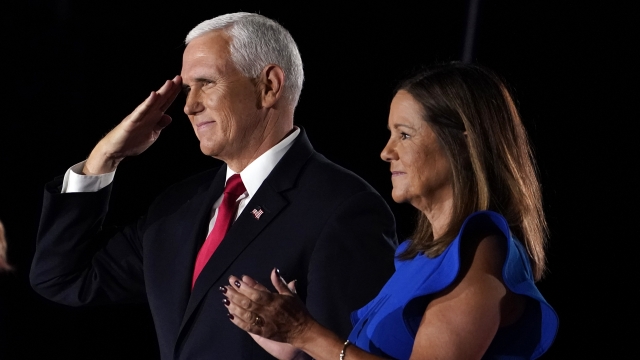 Vice President Mike Pence salutes on stage with his wife Karen after speaking at the Republican National Convention.