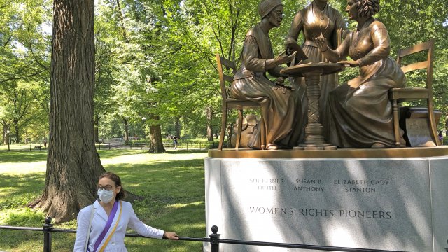 Sculptor Meredith Bergmann stands next to her statue honoring three suffragettes after it was unveiled in Central Park