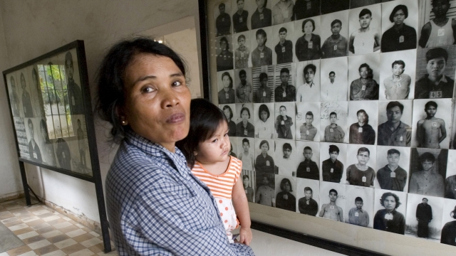 Woman stands next to portraits of former prisoners