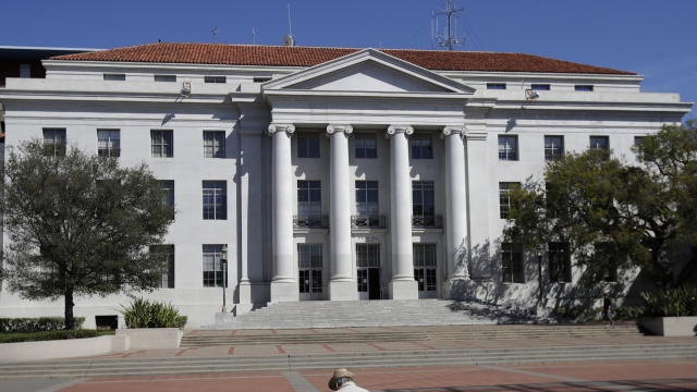 man sits across from Sproul Hall on the University of California campus in Berkeley, California.