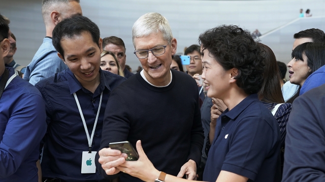 Apple CEO Tim Cook looks at an iPhone 11 Pro Max