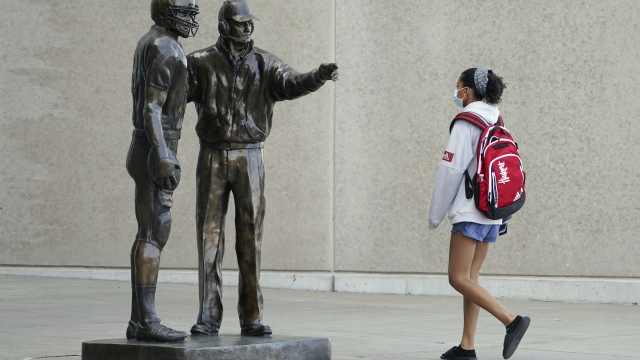 Mask-wearing student walks past statue of legendary University of Nebraska football coach Tom Osborne on Tuesday.