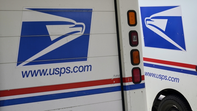 Mail delivery vehicles are parked outside a post office in Boys Town, Neb.