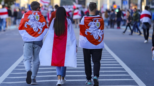 Protesters wear old Belarusian national flags walk during an opposition rally to protest the presidential election results