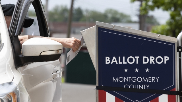 Voters puts ballot in drop box.