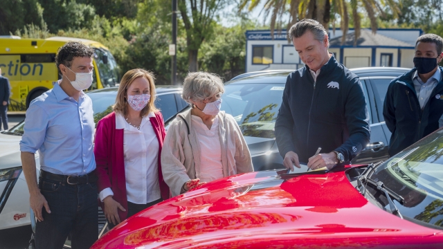 California Gov. Gavin Newsom signs an executive order on the hood of an electric car.