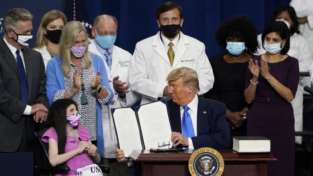President Donald Trump holds up an executive order after delivering remarks on healthcare at Charlotte Douglas International