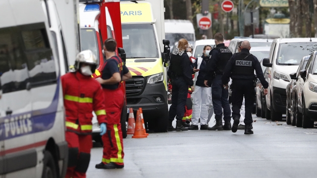 French police officers and rescue workers gather a knife attack near the former offices of satirical newspaper Charlie Hebdo.