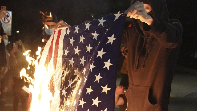 A protester burns an American flag while rallying at the Mark O. Hatfield United States Courthouse on Saturday, Sept. 26