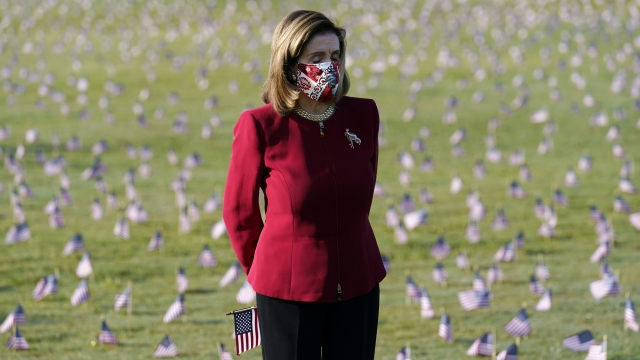 Nancy Pelosi looks at flags representing lives lost from COVID-19