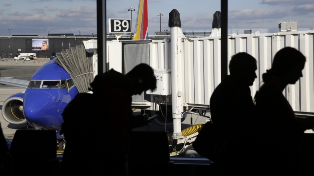 Travelers wait in line to board a flight.