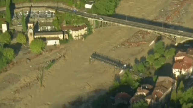 Aerial showing flooded valley, damaged bridge, flooded houses, mudslide, collapsed mountain, damages and debris