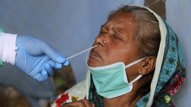 A health worker takes a nasal swab sample of a woman at a testing facility for the coronavirus in a hospital in Pakistan.