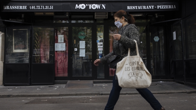 Woman walks by closed case in Paris on Tuesday.