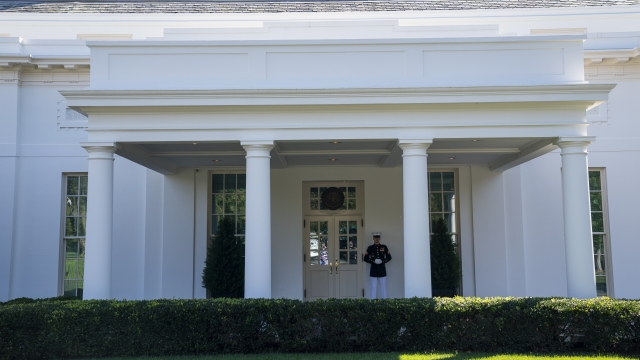 A Marine is posted outside the West Wing of the White House, signifying the President is in the Oval Office