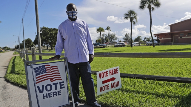 A former felon stands next to voting sign.