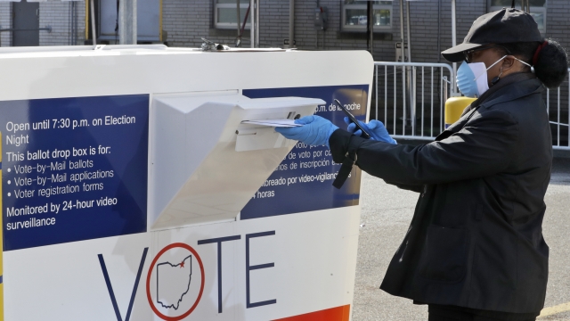 Marcia McCoy drops her ballot into a box outside the Cuyahoga County Board of Elections in Cleveland, Ohio