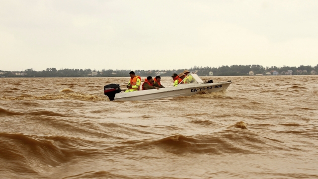 Rescue workers travel by boat on a swelling river to access a flooded area in Vietnam