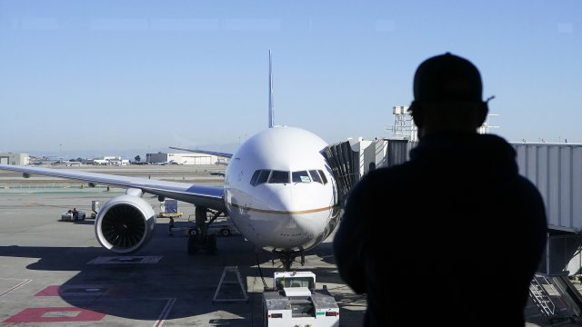 A man looks out of a window toward a United Airlines flight.