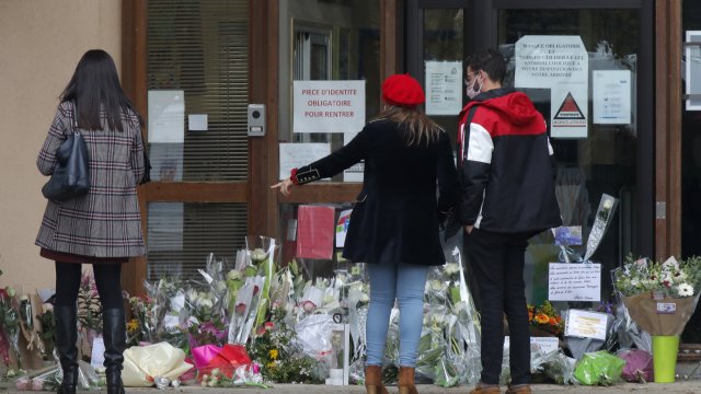 Mourners gather outside a French school after a teacher was decapitated