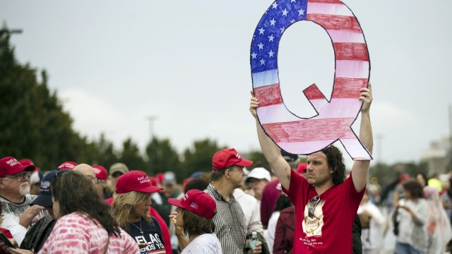 A protester at a Trump campaign rally holds a Q sign.