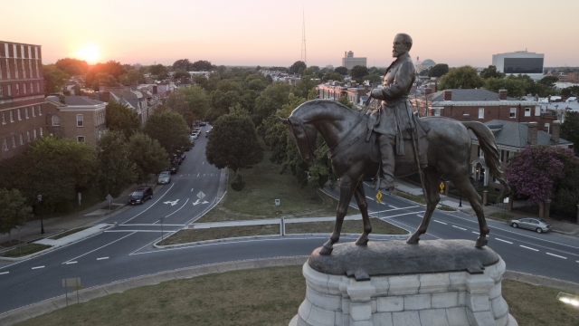 The sun sets behind the statue of Confederate Gen. Robert E. Lee on Monument Avenue in Richmond.