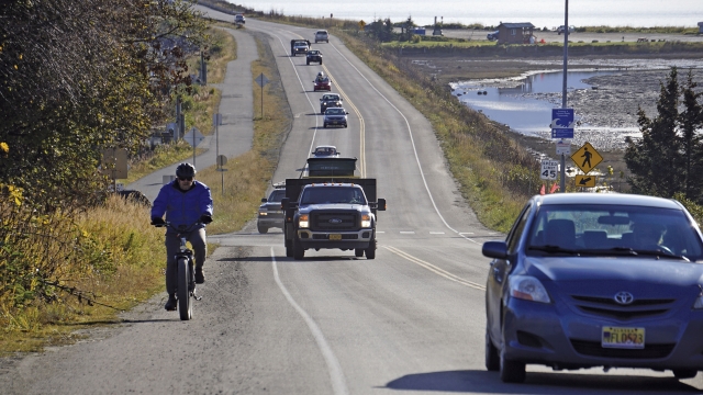 A biker leads a line of cars driving on Monday, Oct. 19, 2020, in Homer, Alaska after a tsunami evacuation.