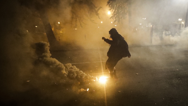 A demonstrator kicks a tear gas canister back at federal officers during a Black Lives Matter protest in Portland, OR July 20