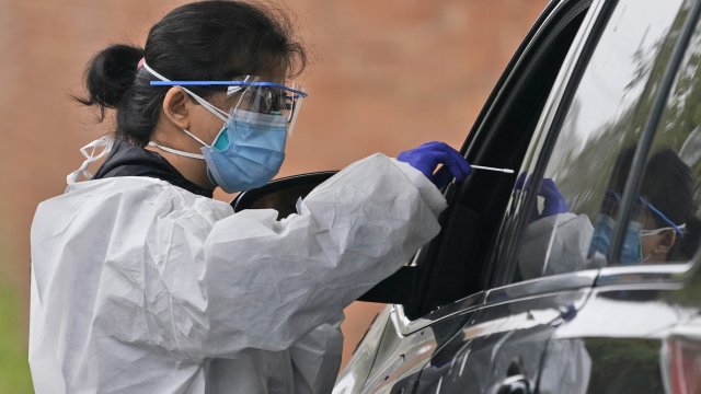 Medical personnel prepare to administer a COVID-19 swab at a drive-through testing site in Lawrence, N.Y.,