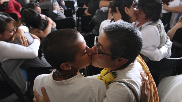 Gay and lesbian couples kiss after getting married