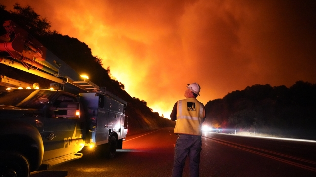 A Pacific Gas and Electric worker looks at the fire advancing along a northern California highway.
