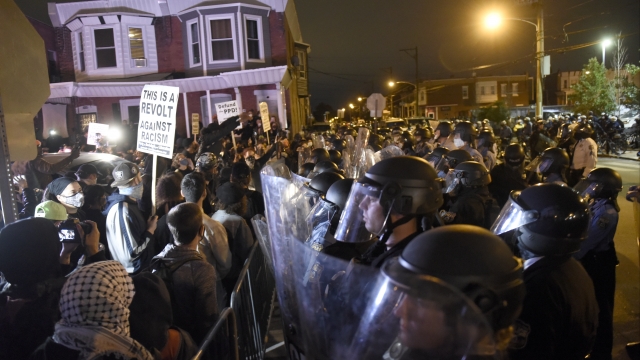 Protestors face off with police in Philadelphia. Sign says "This is a revolt against racism."